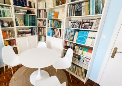 Sala polivalente en lapiz desarrollo para talleres y terapia grupal con mesas blancas, sillas modernas y estanterías llenas de material didáctico