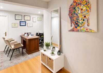 ista del despacho de psicología en Abril Psicología con escritorio de madera, sillas para pacientes y decoración relajante con un Buda colorido.